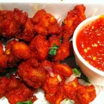 Spicy and crispy Chicken 65 served hot with garnishing of curry leaves and green chilies.